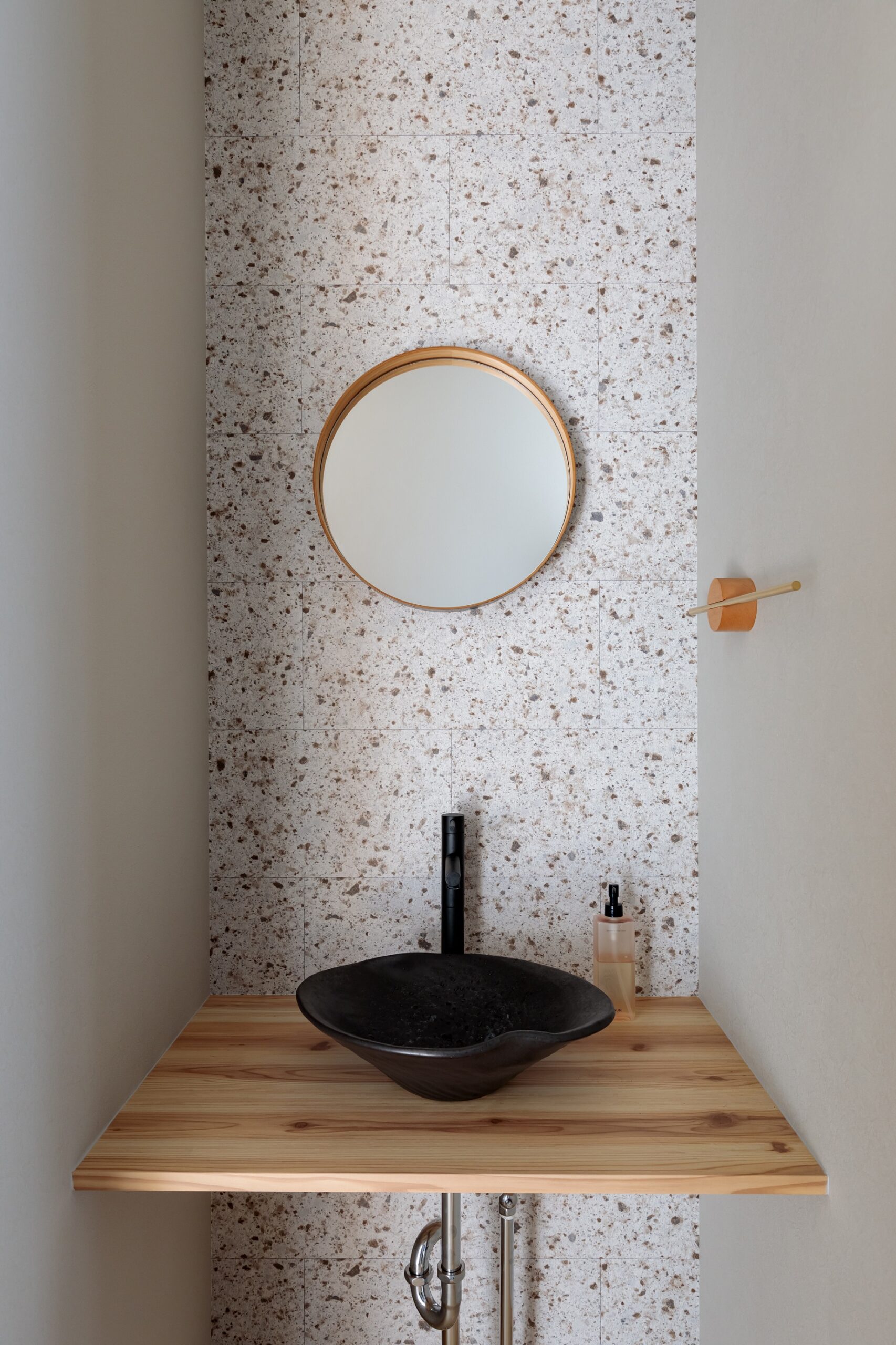お客様のおもてなしスペースにもなる、トイレの手洗いを兼ねた洗面コーナー。コストを抑えながらN様がお好きな大谷石のデザインを取り入れるため、近しい雰囲気のアクセントクロスを探してご提案しました。