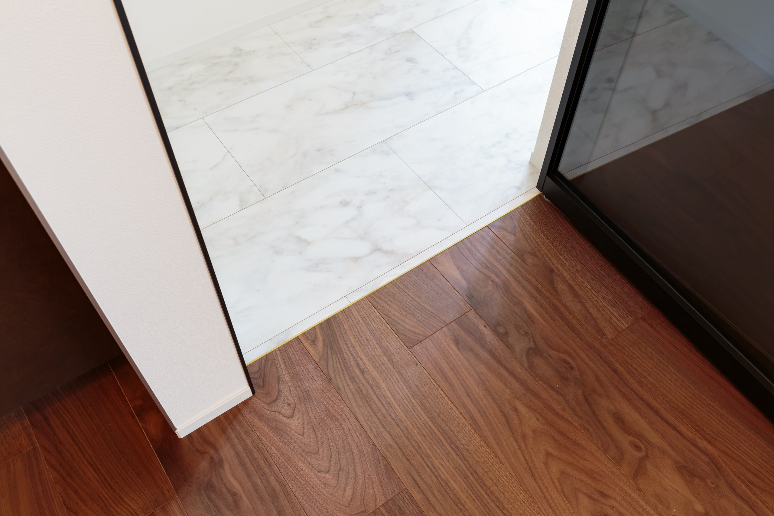 LDKは木目が美しく足ざわりのいいフローリング、水回りは掃除がしやすいフロアタイルと、用途で床材を使い分けることも暮らし心地を高めるアイデアの一つ。真鍮の見切り材をアクセントに採用しました。
